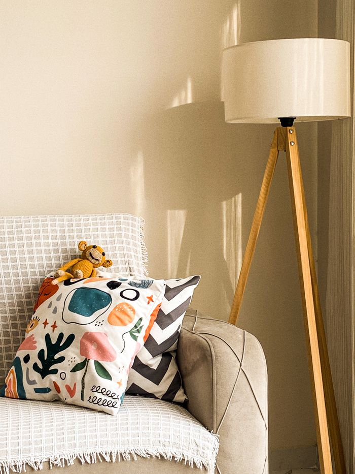 A stylish cozy corner featuring a modern lamp and abstract pillows, perfect for interior design inspiration.