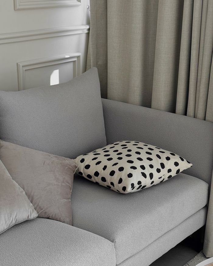 Stylish gray sofa adorned with modern polka dot and beige cushions in a chic interior setting.