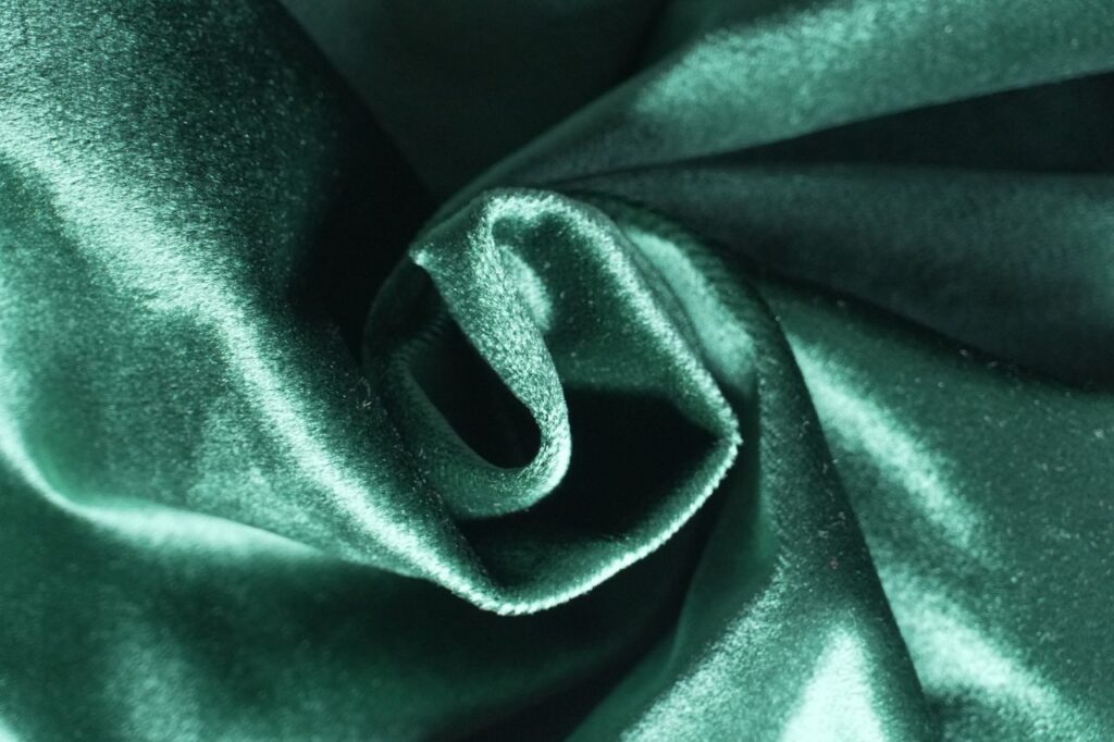 Close-up of emerald green velvet fabric showcasing its luxurious sheen and texture, perfect for design projects.