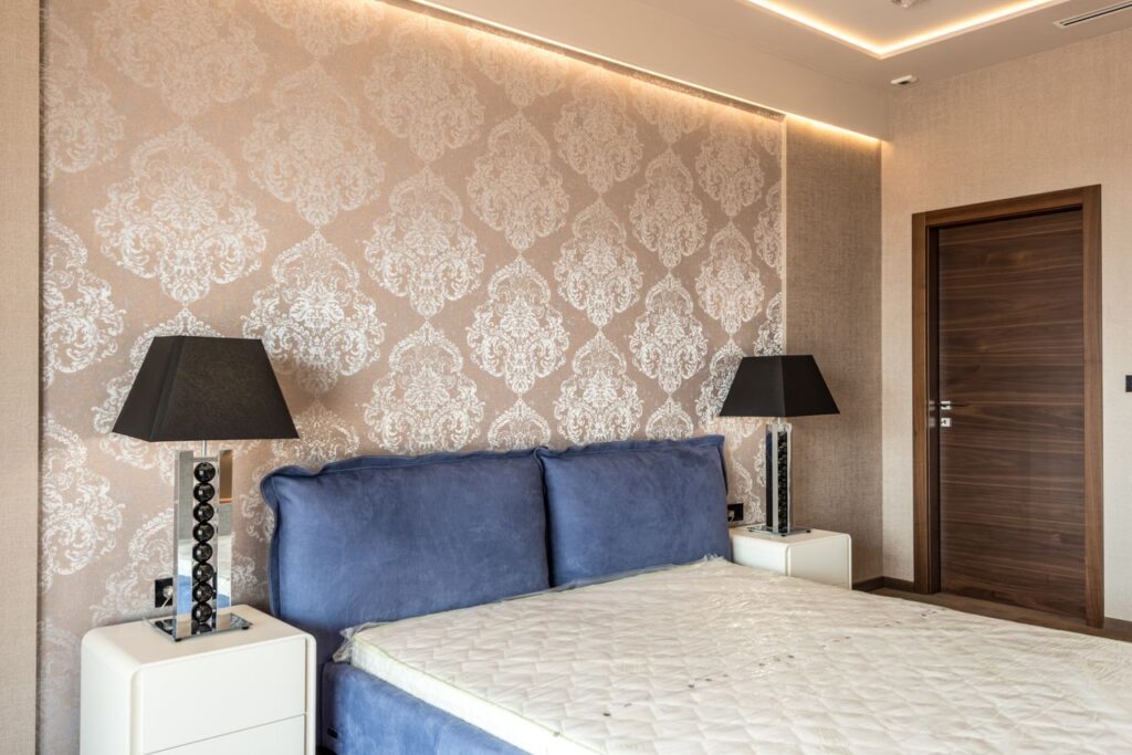 🧱 Premium Wallpapers Modern bedroom featuring elegant wallpaper, blue headboard, and stylish black lamps for a contemporary look.