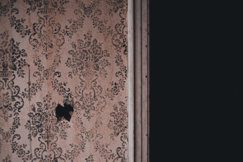 🧱 Premium Wallpapers Close-up of an aged floral wallpaper with a small hole, offering a rustic and nostalgic feel.